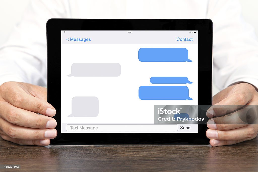 Empresário segurando um computador tablet com as conversas por sms no ecrã - Royalty-free Adulto Foto de stock