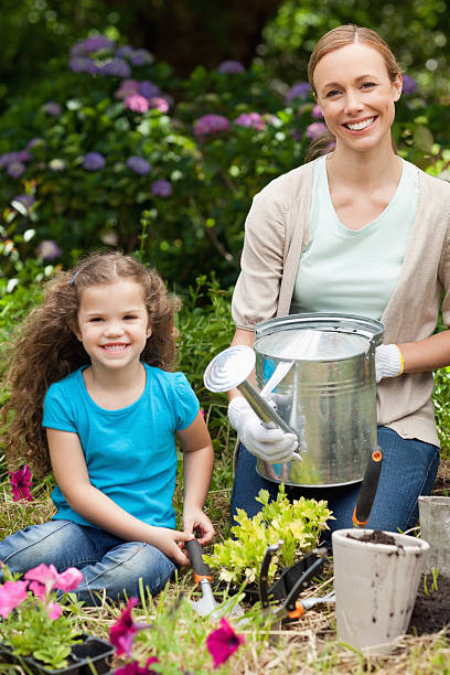 istock Woman holding a watering can while sitting with her daughter 456240949