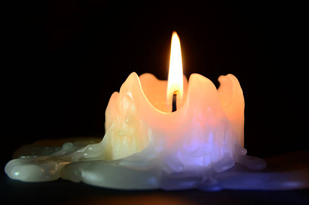 Candle in the Dark Closeup of a melting candle with black background. candle wax stock pictures, royalty-free photos & images