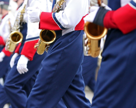 A line of high school saxophone players marching in a Christmas parade.