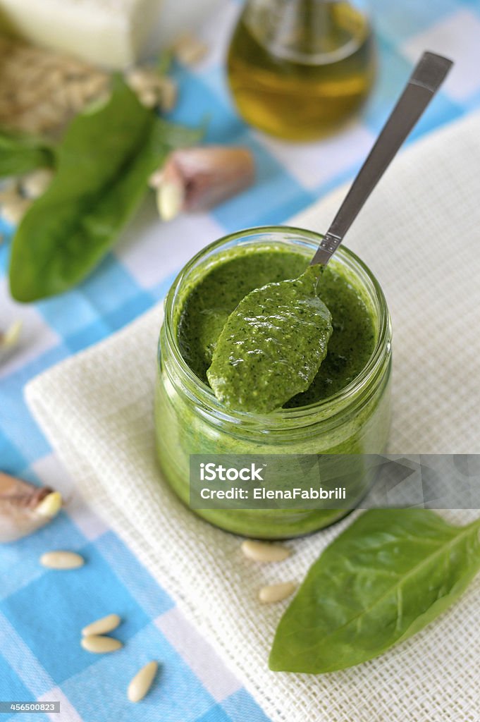 Spinach pesto Spinach pesto in a glass jar, decoration: spinach leaves, pine nut, cheese Parmesan, garlic, olive oil. Appliance Stock Photo