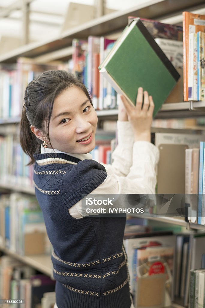 Frau, die ein Buch aus Bücherregal - Lizenzfrei Akademisches Lernen Stock-Foto