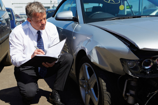 Loss Adjuster Inspecting Car Involved In Accident and taking notes
