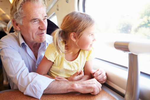 Grandfather And Granddaughter Relaxing On Train Journey looking out the window