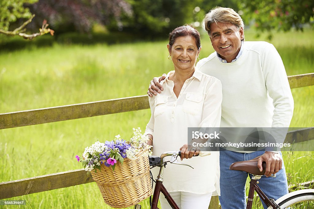 Senior Indian Couple On Cycle Ride In Countryside Senior Indian Couple On Cycle Ride In Countryside standing close together Cycling Stock Photo