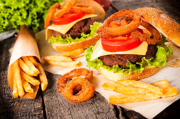 Burger time Big and tasty beef burger with onion rings and french fries.Selective focus on the burger fried onion rings stock pictures, royalty-free photos & images