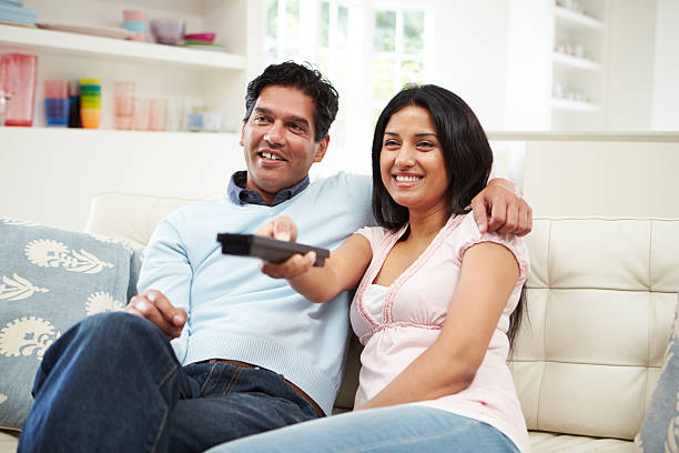 istock Indian Couple Sitting On Sofa Watching TV Together 456541659