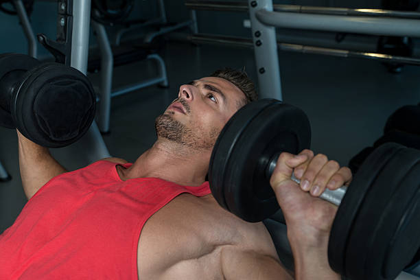 istock Man Lies On A Bench And Does Dumbbell Presses 456565553