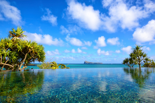 Exotic landscape view with palm trees reflected in surface of water in pool on tropical paradise Koh Tao island during the orange sunset