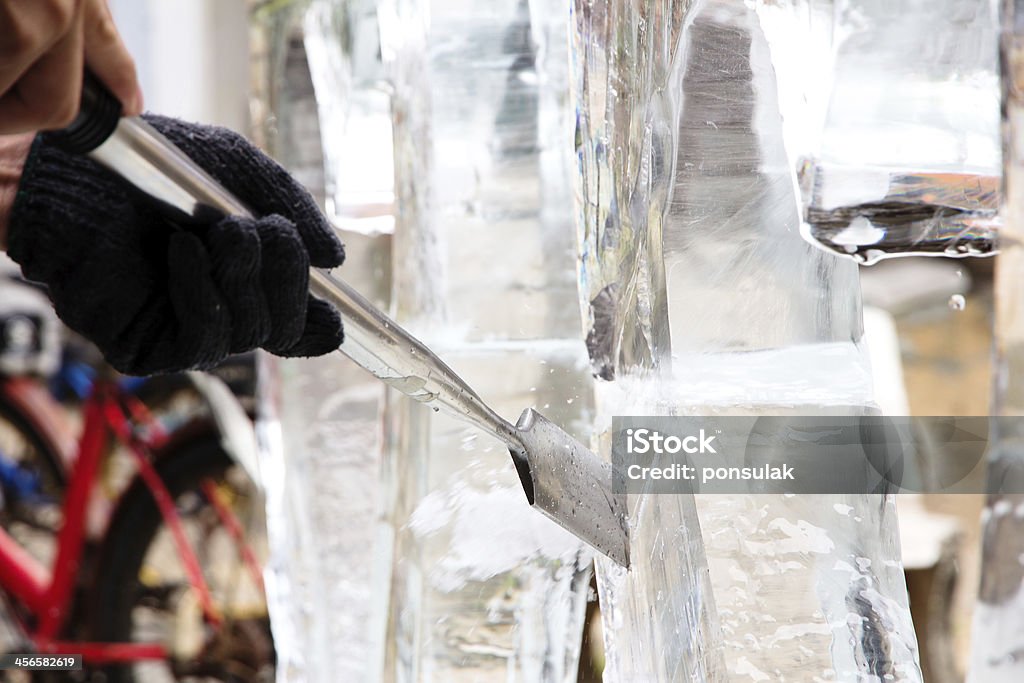 Ice Carver Using Chisel to Carve Ice Sculpture Stock Photo