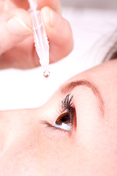 istock A woman inserting eye drops into her eye 456748725
