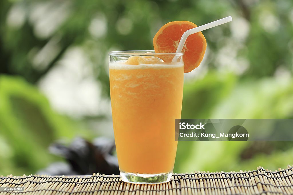 Orange Smoothie Glass of Orange Smoothie on garden background Blended Drink Stock Photo