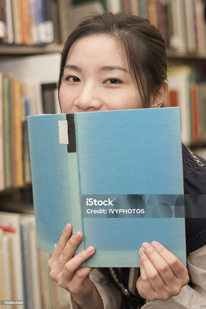 Studente che copre la bocca con libro - Foto stock royalty-free di Adulto