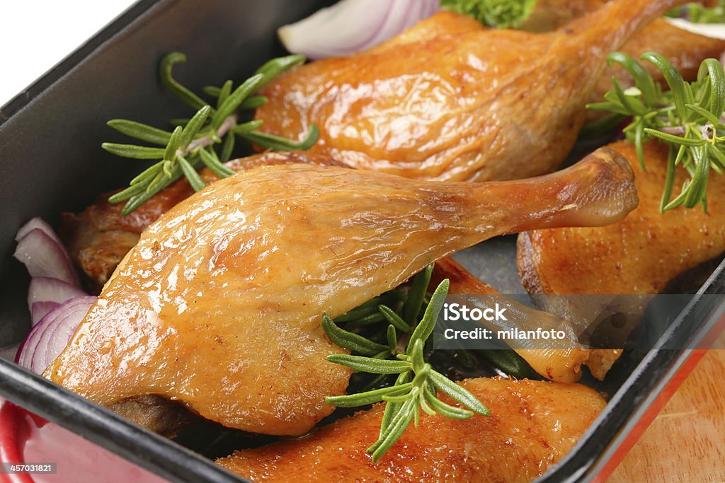roasted duck legs detail of roasted duck legs with onion, garlic and herbs in baking tin Animal Body Part Stock Photo