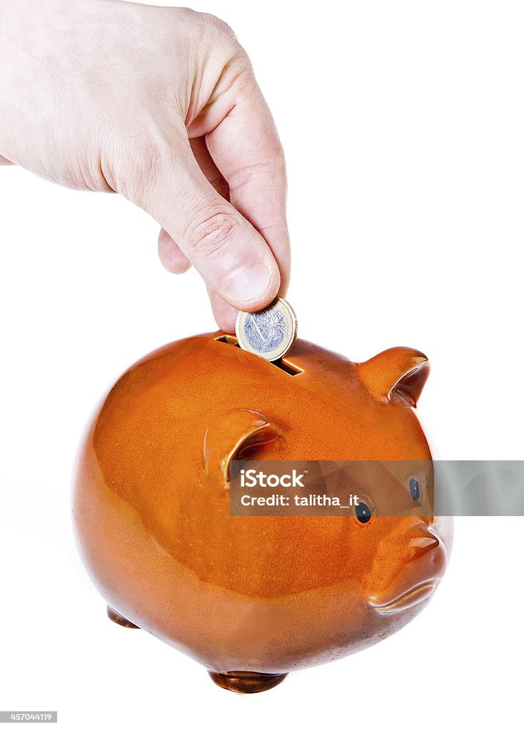 Male hand putting coin into a piggy bank Male hand putting coin into a piggy bank isolated on a white background Bank Account Stock Photo