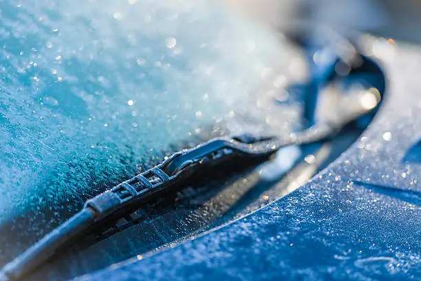 Frozen windshield, cold weather, sunlight on backlight, focus on foreground