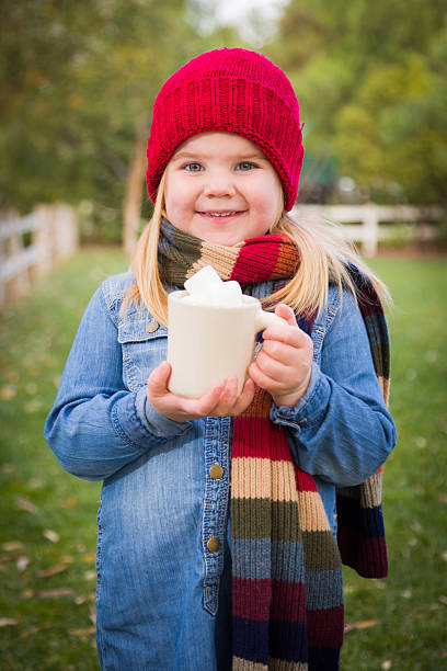 istock Cute Young Girl Holding Cocoa Mug with Marsh Mallows Outside 457074367