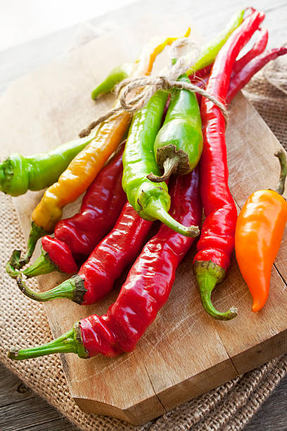 istock Colored hot chilli peppers on wooden chopper 457088147