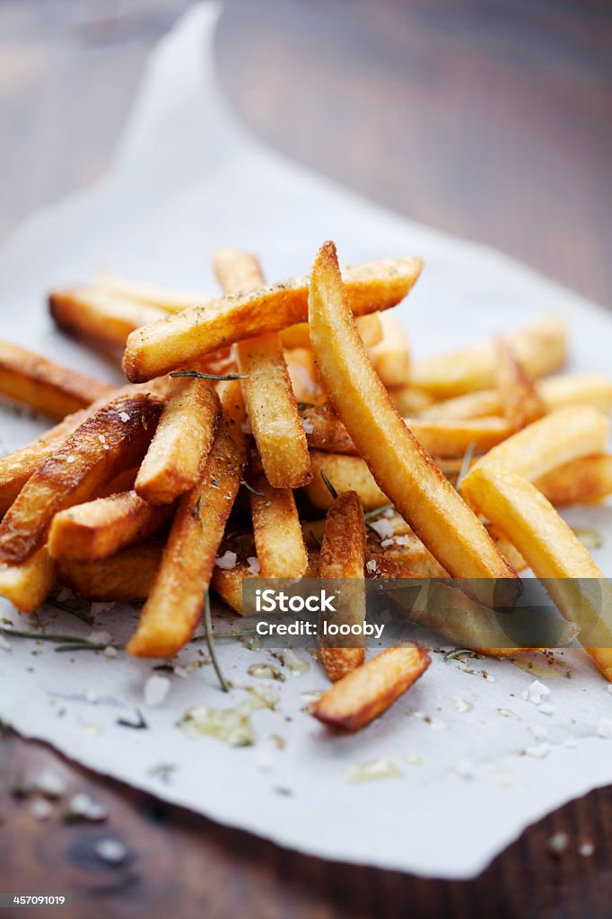 Seasoned french fries served on white butcher's parchment golden crispy french fries with salt and herbs French Fries Stock Photo