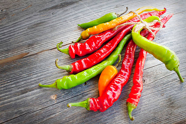 istock Colored hot chilli peppers on wooden textured background 457095809