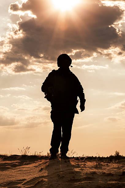 Silhouette Silhouette of young soldier in military helmet against the sun infantry stock pictures, royalty-free photos & images
