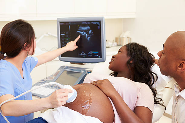 pregnant woman and partner having 4d ultrasound scan - hamile stok fotoğraflar ve resimler