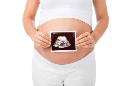 An ultrasound print in front of pregnant woman's belly. Isolated on a white background.