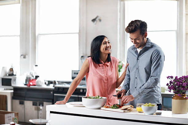 couple preparing food in kitchen - standing smiling two people 30s fotografías e imágenes de stock