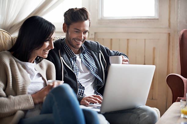 couple looking at laptop - couple home interior laptop computer imagens e fotografias de stock