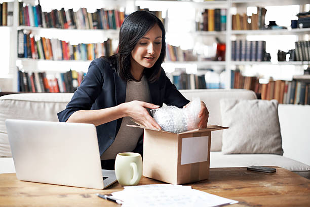 woman preparing parcel for shipment - book sofa women bookshelf 뉴스 사진 이미지