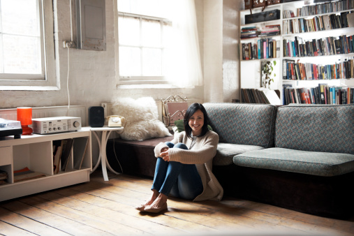 Portrait of woman sitting on the floor of her cozy loft apartment