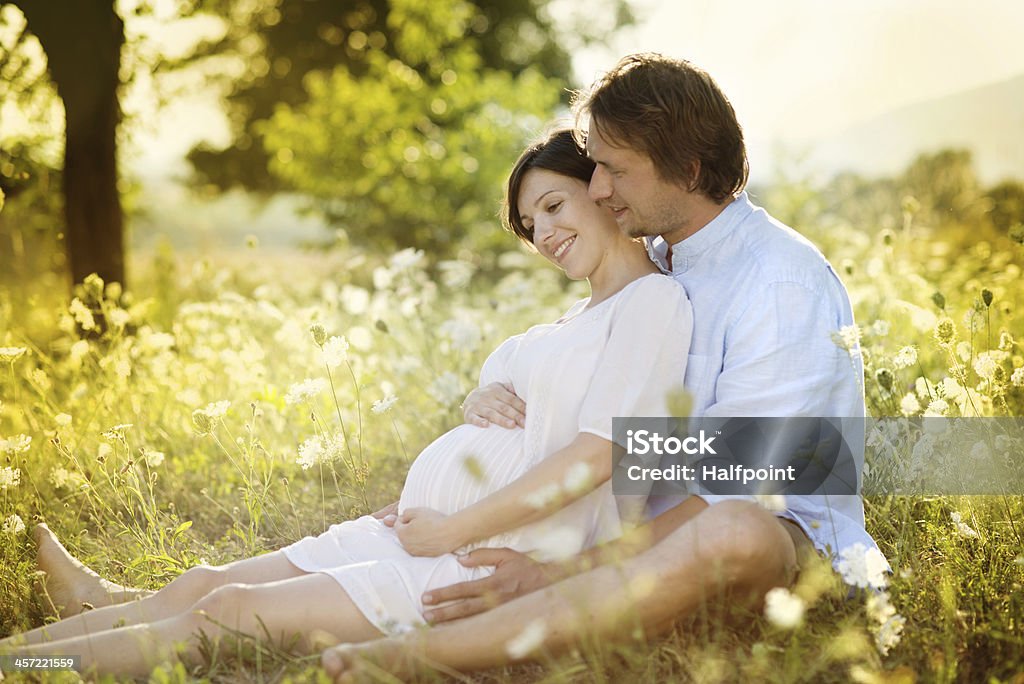 Pregnant woman with man in field Happy young pregnant couple hugging in nature Consoling Stock Photo
