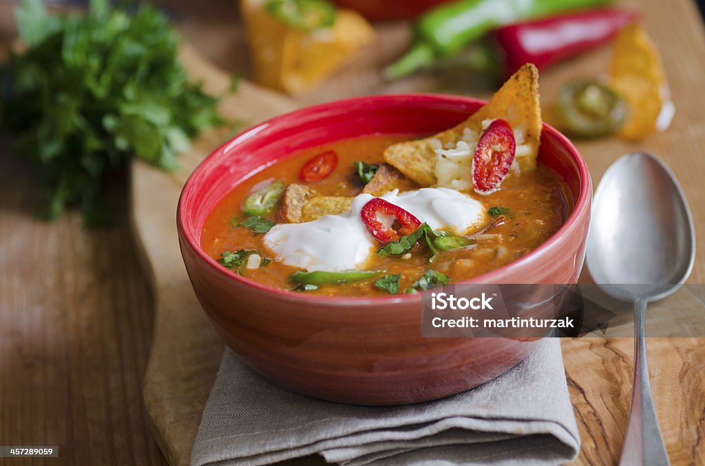 A bowl of Ranchero chicken topped with chips Spicy Mexican chicken soup with tortilla chips and chilli peppers Soup Stock Photo