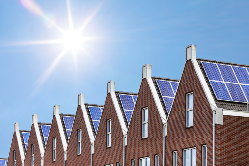 Newly build houses with solar panels attached on the roof against a sunny sky