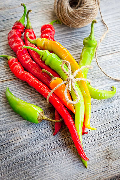 istock Colored hot chilli peppers on wooden textured background 457330729