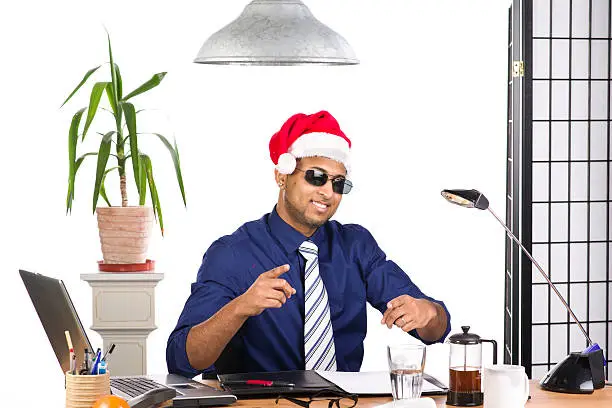 An image of an Indian office worker with a blue shirt behind his desk