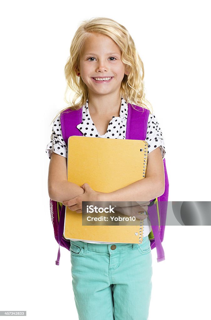 Cute Elementary School Girl An isolated photo of a cute elementary school girl wearing a backpack and carrying a notebook Ring Binder Stock Photo