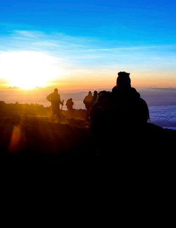 A team of trekkers approaching Uhuru Peak, 5896m, on Kilimanjaro just as sunrises. The group had climbed through the night to watch the sunrise
