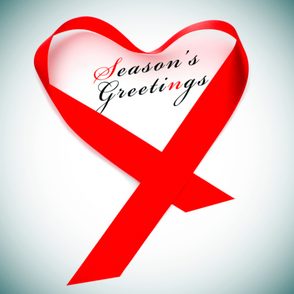 a red satin ribbon forming a heart and the sentence seasons greetings