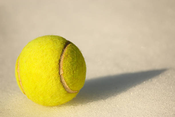 istock Tennis ball on snow with its shadow 457391587