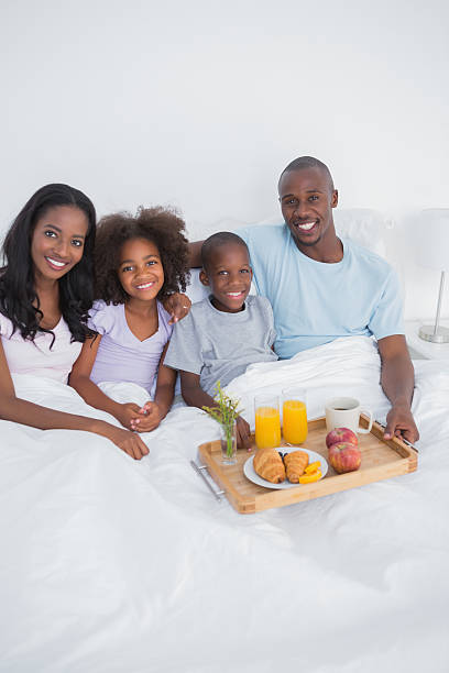 istock Cute family having breakfast in bed looking at camera 457394181
