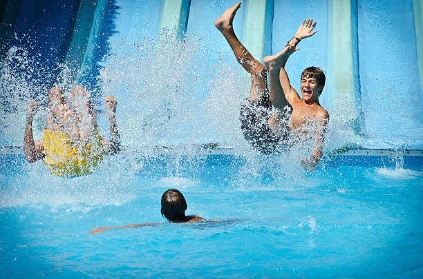 Jóvenes divirtiéndose por toboganes acuáticos en el parque acuático - foto de stock