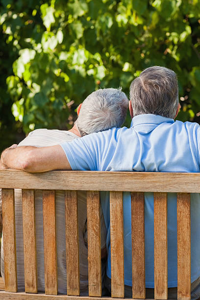 istock Elderly couple cuddling while sitting on a bench 457402025