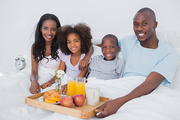 istock Smiling family having breakfast in bed looking at camera 457402083