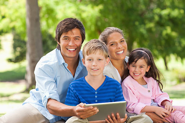 istock Smiling young family with a tablet computer looking at camera 457402103