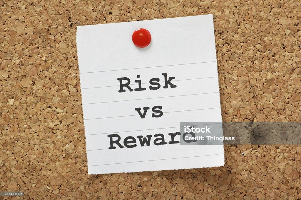 Risk Vs Reward The phrase Risk vs. Reward typed onto a piece of lined paper and pinned to a cork notice board. Incentive Stock Photo
