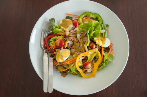 Tuna and vegetable salad with egg on wooden table with pumpkin dressing