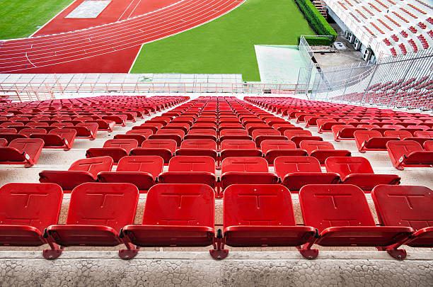 istock Red stadium seats with running track and green grass. 457423813