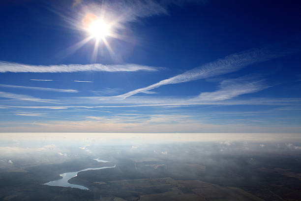 Aerial view from airplane window at high altitude of earth covered with white puffy cumulus clouds.