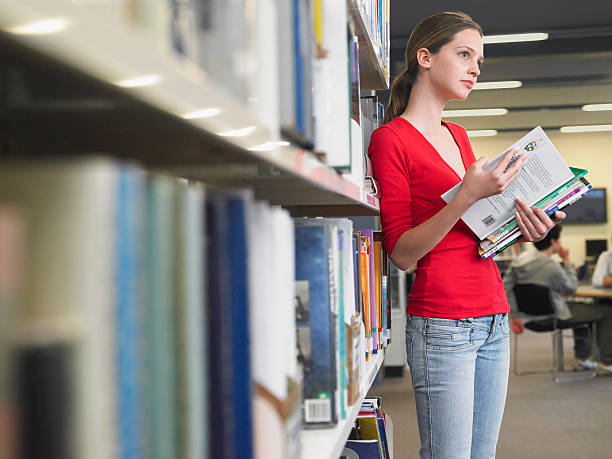 College students standing in front of bookshelfs and choosing a book.